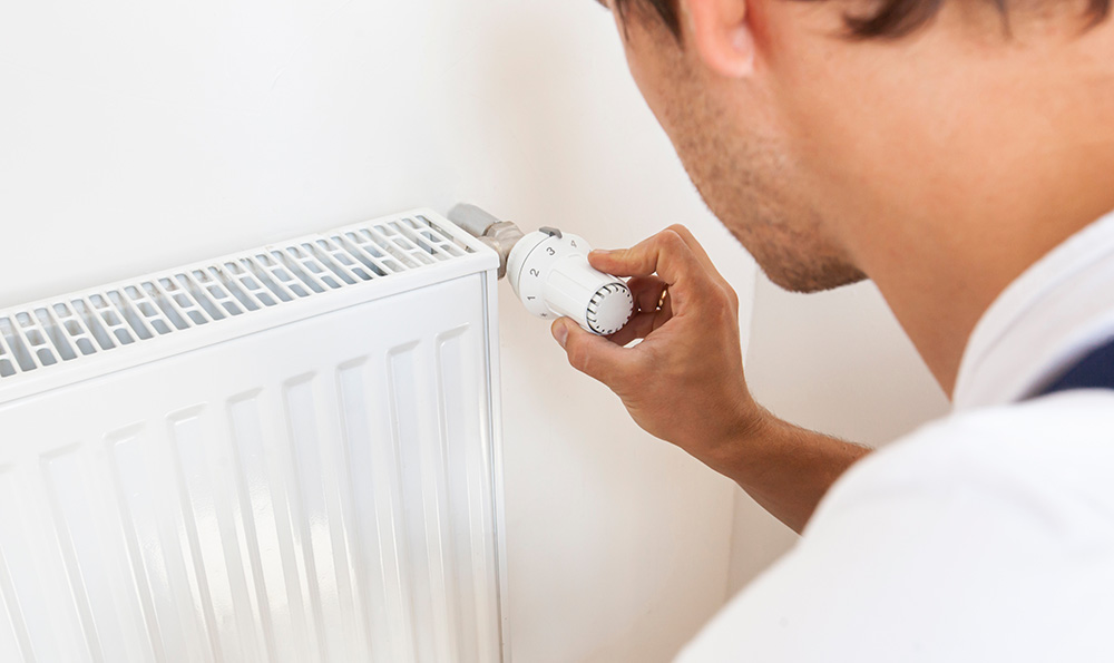 Photo d'un plombier réglant la température d'un radiateur - désembouage radiateur