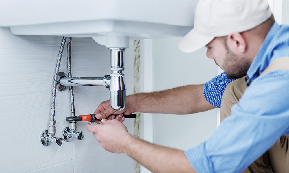 Image d'un plombier réparant les tuyaux flexibles du lavabo - Catégorie curage canalisation